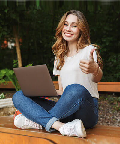 Mi primer trabajo - Joven chica sonriendo sentada mientras que utiliza en portátil