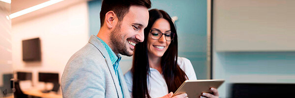 Cash Pooling - Hombre de traje sonriendo junto a una mujer de gafas sonriendo en oficina Cash Pooling - Hombre de traje sonriendo junto a una mujer de gafas sonriendo en oficina