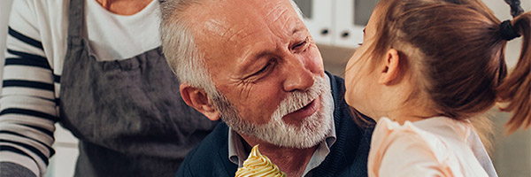 Programa Impulsa Senior  - Abuelos me edad avanzada en la cocina de su casa con su nieta cocinando galletas y sonriendo