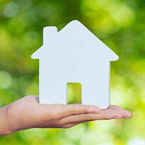 Moratoria Legal - Con garantía hipotecaria. Silueta de casa sobre mano de una mujer con fondo arbolado Moratoria Legal - Con garantía hipotecaria. Silueta de casa sobre mano de una mujer con fondo arbolado