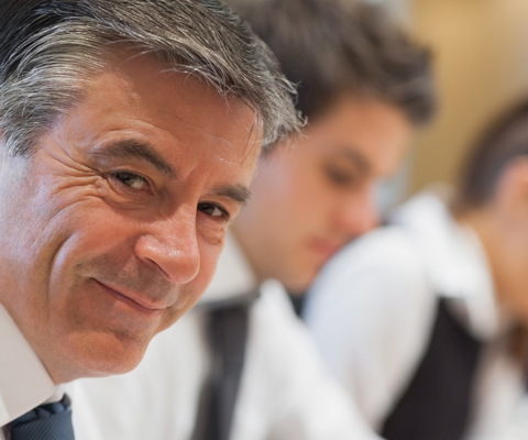 Subvenciones y ayudas - Ejecutivo sonriendo en una reunión Subvenciones y ayudas - Ejecutivo sonriendo en una reunión